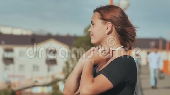 一个年轻的女孩戴着白色耳机在一个温暖的夏天晚上愉快地听音乐视频的预览图