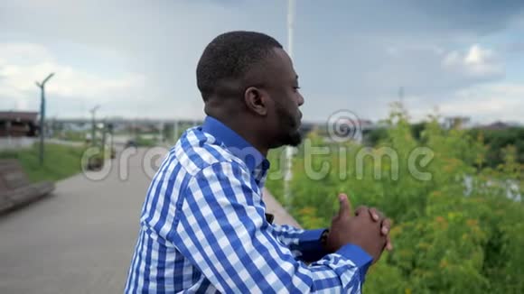 黑人站在公园围栏附近的城市海滨欣赏城市景色视频的预览图