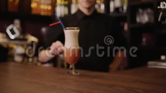塔普斯特为游客介绍和带来成品鸡尾酒把玻璃推到酒吧桌上的摄像机前视频的预览图