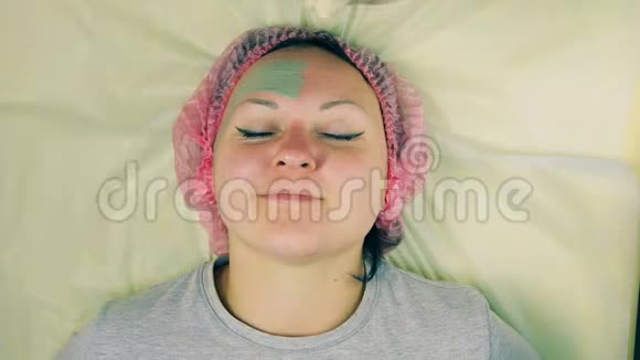 时光流逝化妆师的男人的手在女人的脸上放了一个蓝色粘土的液体面具借助刷子视频的预览图