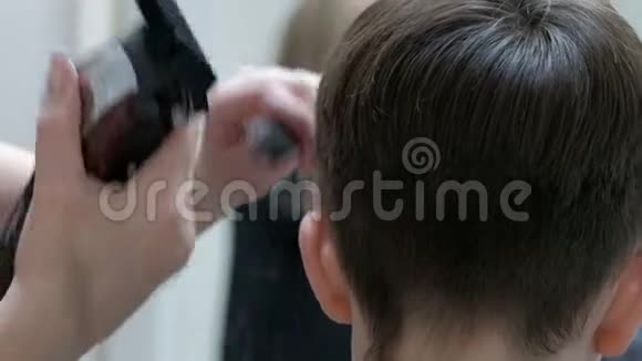 在一家美发沙龙里一个青少年的头部特写镜头理发师用电剪子剪一个年轻人的头发视频的预览图