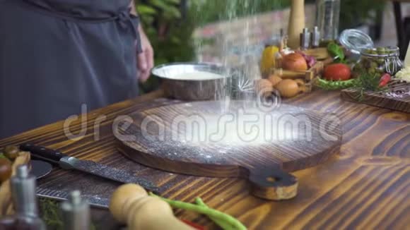 面包师在厨房桌子上的木板上倒白面粉食物和蔬菜背景厨师洒面粉视频的预览图