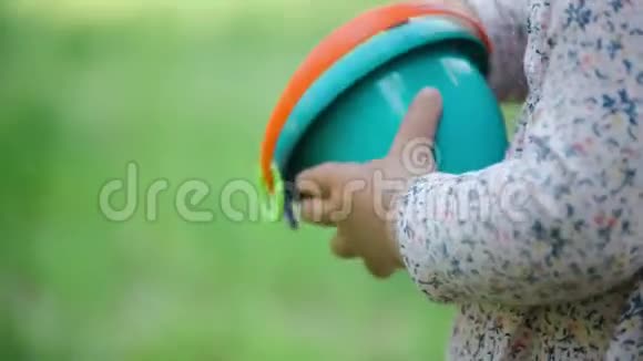 孩子拿着沙桶靠近绿色模糊的背景夏日视频的预览图