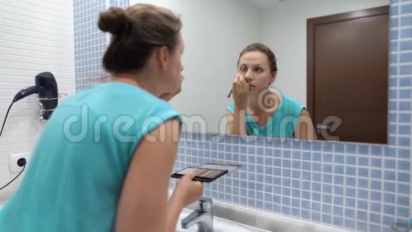 漂亮女人在浴室镜子前用眼影和化妆刷做眉毛化妆视频的预览图