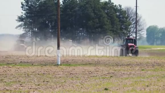 两台红色拖拉机在炎热干燥的天气下对电力线路的柱子进行土壤处理视频的预览图