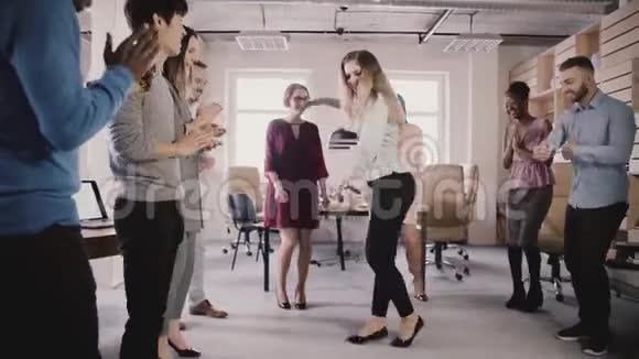 快乐的欧洲女孩在有趣的办公室聚会上跳月游舞多民族商人庆祝成功慢动作视频的预览图