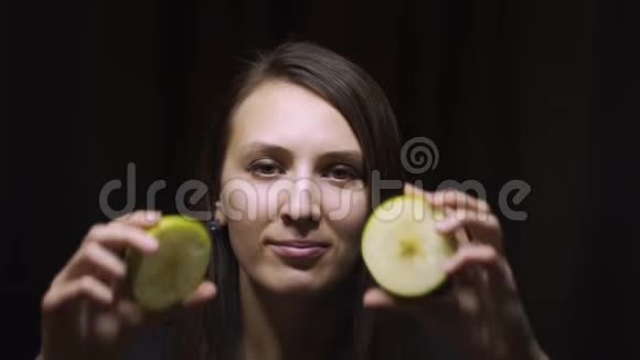 一个深黑的背景下一个深黑的女孩眼睛上戴着一个苹果水果健康饮食饮食眼部健康理念视频的预览图