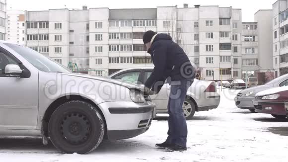 一个人不能打开车里卡住的引擎盖冬天问题雪视频的预览图