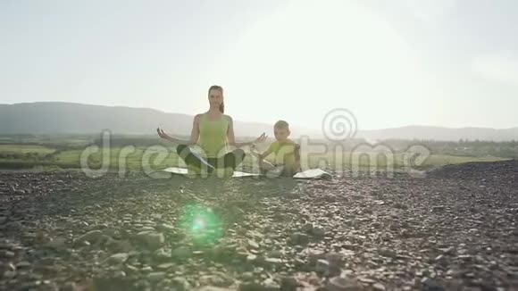 小儿子和妈妈早上在山顶户外做瑜伽和冥想视频的预览图