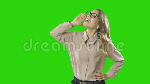 金发年轻漂亮的女孩向公司举手唱歌或喊叫在一个孤立的绿色背景上射击视频的预览图