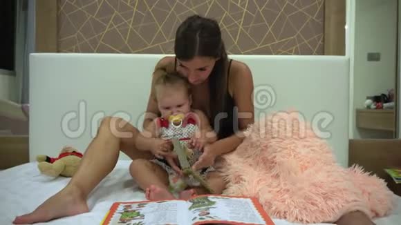 母亲和她可爱的女儿正坐在客厅的沙发上他们重新阅读儿童书视频的预览图