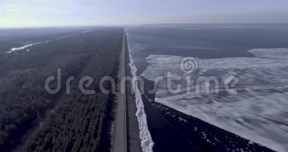鸟瞰冰冰冰川近海岸的冬季冻海森林与冬季树木和道路视频的预览图