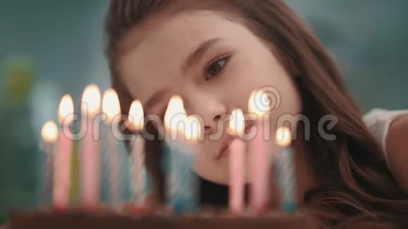 漂亮的女孩慢慢地在生日蛋糕上吹蜡烛火焰生日快乐视频的预览图