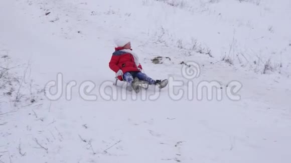 穿着红色夹克的快乐孩子穿着雪橇滑过雪地笑了起来快乐的女孩在圣诞假期里玩耍视频的预览图