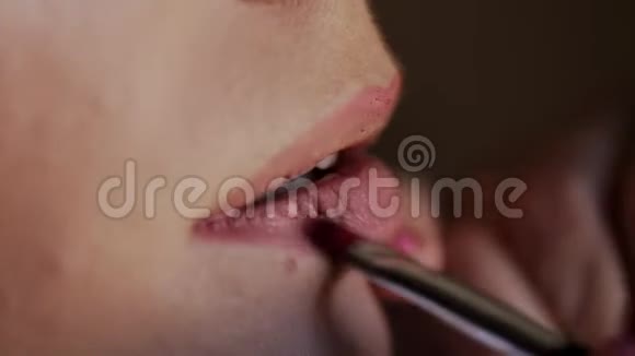 化妆师大师用一支特殊的铅笔用口红涂嘴唇新娘婚礼准备化妆视频的预览图