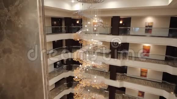 一个昂贵的美丽的城市酒店一个金色的螺旋吊灯与电梯在大厅的中心从顶端视频的预览图