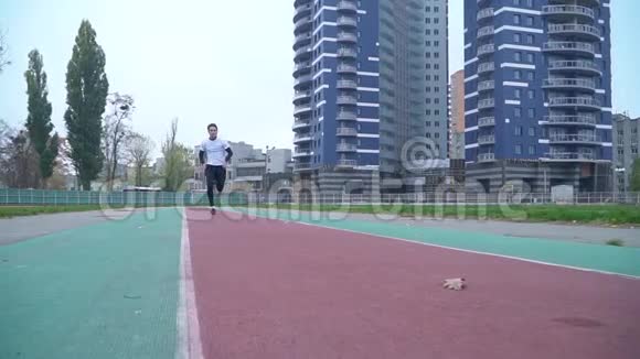 穿着运动服的年轻人很快就跑到室外的摄像机前运动男在体育馆里跑来跑去视频的预览图