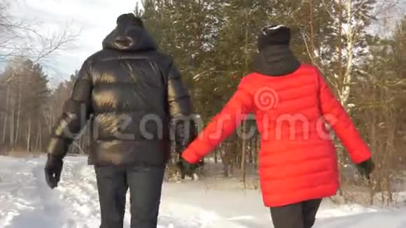 幸福的一对男女牵着手走在白雪皑皑的冬林中视频的预览图