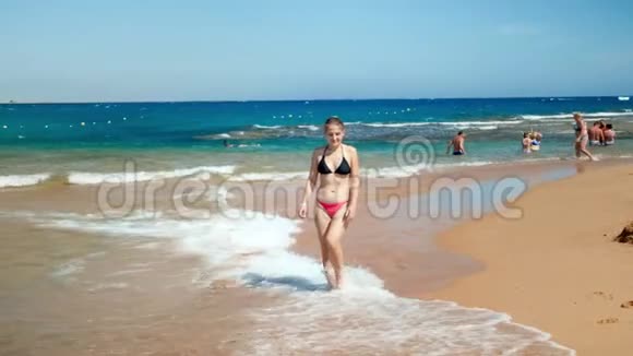 美丽的比基尼女郎在阳光明媚的一天在沙滩上散步的4镜头视频的预览图