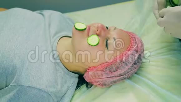 时光流逝化妆师的男人的手在女人的脸上放了一个面具桃和黄瓜片的面具视频的预览图