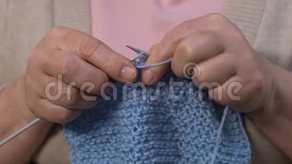 老年妇女为丈夫编织蓝围巾退休爱好双手合拢视频的预览图