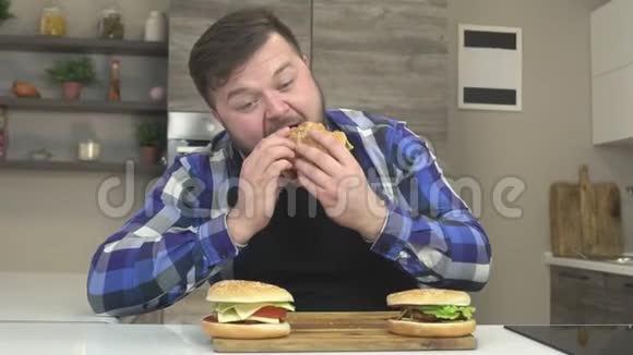 一个长着胡子的胖子在厨房里吃汉堡额外的卡路里慢动作暴食视频的预览图