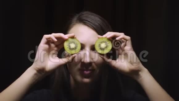深色背景下一个深褐色头发的女人眼睛上戴着猕猴桃视频的预览图