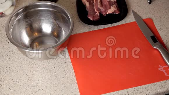 女性手在桌子上切猪肉准备晚餐视频的预览图