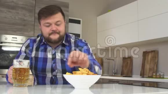 有胡子的男人在厨房里喝啤酒夹薯片特写肥胖慢动作女性荷尔蒙视频的预览图