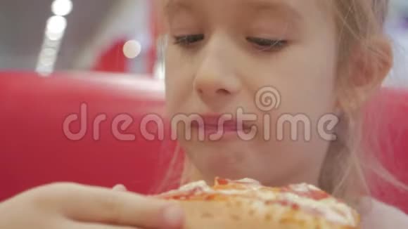 一个有辫子的年轻女孩正在吃一块披萨可爱快乐的小女孩笑着咬着一大块新鲜的视频的预览图