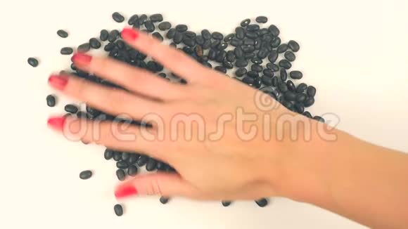 女人双手从黑豆中形成心脏视频的预览图