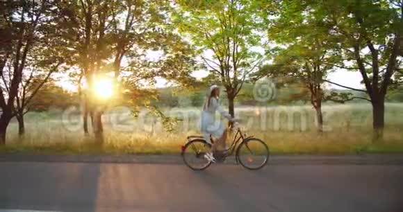 骑自行车的妇女在乡村路日落视频的预览图