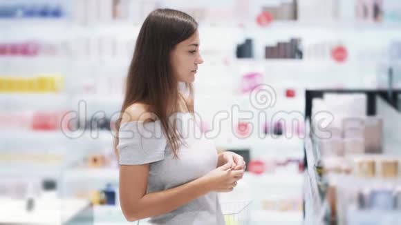 年轻女子在化妆品店里选择香水喷香水嗅香水慢动作视频的预览图
