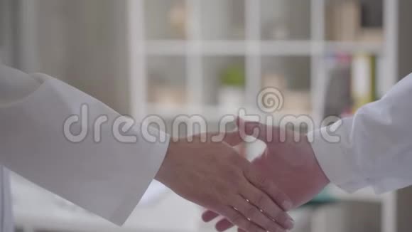 像医生一样两只穿着白大褂未被认出的男性手自信友好地握手医学健康概念视频的预览图