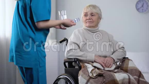 年轻护士给轮椅上的老太太送药康复中心视频的预览图
