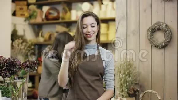 女孩站在一家花店里调整头发相机从远处向近处移动视频的预览图