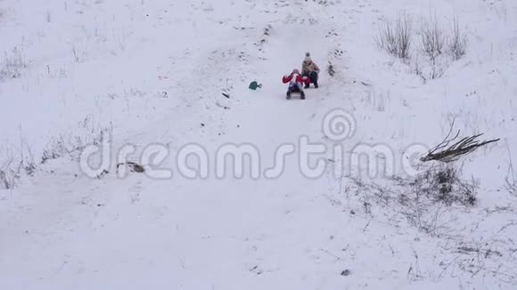 在冬天的公园里孩子们在圣诞假期骑雪橇下山视频的预览图