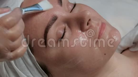 一个闭着眼睛的漂亮女孩的特写脸躺在医学美容程序上一个美容师和一个视频的预览图