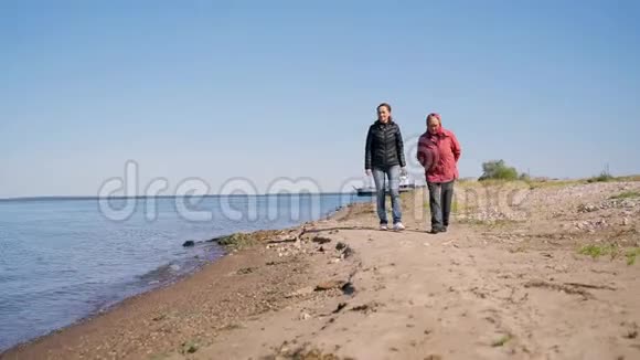 一位年迈的妇女带着一个成年的女儿沿着海岸散步在一个秋天的日子里她愉快地交谈着笑着一个年轻人视频的预览图