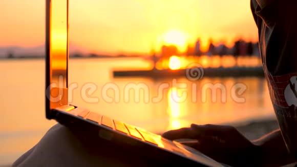 在海边的笔记本电脑上工作的人日落背景上有笔记本的男性从事自然研究的自由职业者视频的预览图
