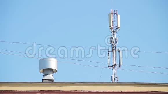 在通风系统旁边的建筑物屋顶上有蜂窝天线的塔一只鸟在蓝天上飞过视频的预览图