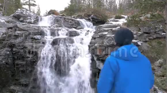 一个人在山上拍摄一个美丽的瀑布在相机上他经常旅行引导一个活跃有趣的视频的预览图