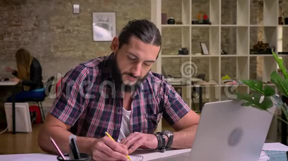 专注于写作的白种人正坐在cna正确地看着他的笔记而坐在桌面上工作视频的预览图
