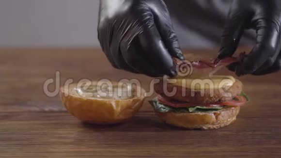 做汉堡特写的厨师的手厨师把洋葱和洋葱放在切块上番茄片和罗勒叶上视频的预览图