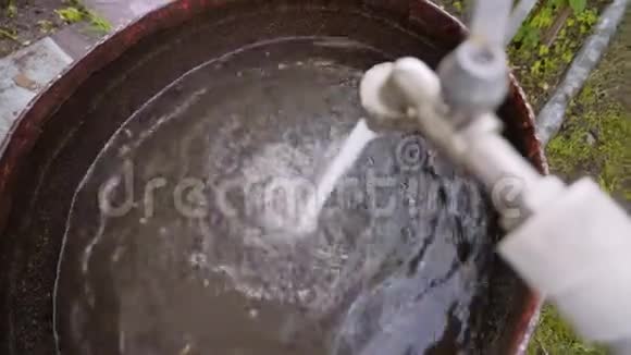 水龙头里的水倒进一个生锈的大桶里在乡下休息水的收集视频的预览图