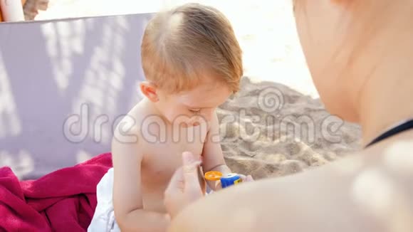 喜笑颜开的家庭在阳光明媚的天气在沙滩上涂抹紫外线防晒乳液4k视频视频的预览图