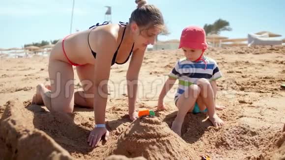 4k慢动作视频年轻母亲在沙滩上放松时与孩子玩耍视频的预览图