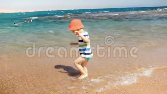 4k镜头欢乐的笑着蹒跚学步的男孩在沙滩上的海浪中玩耍视频的预览图