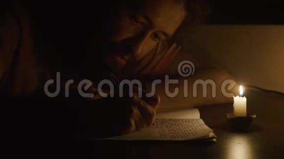 在昏暗的房间里用笔在烛光下写字视频的预览图