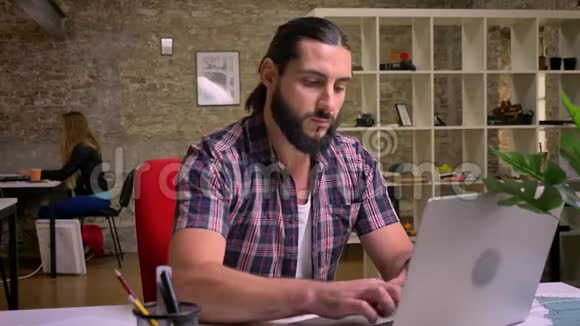可爱集中的白种人商人穿着休闲装黑胡子正在笔记本电脑上打字视频的预览图